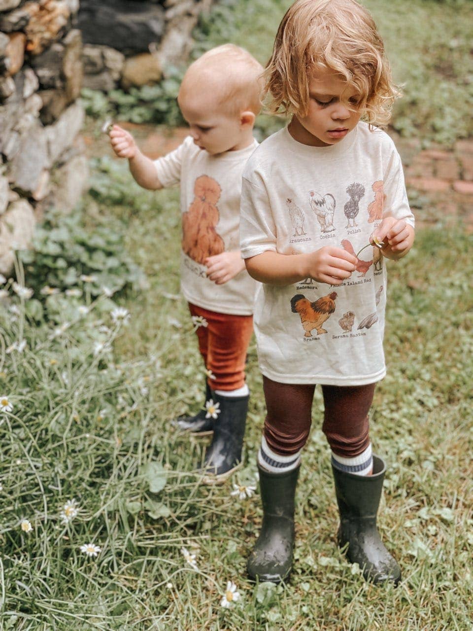 Two children in a garden wearing matching outfits with animal prints.