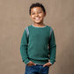 Child wearing a green sweater with white trim against a brown background