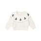 A white fair isle sweater with a pattern of green trees and dots, suitable for babies.