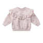 Pink baby sweater with ruffled details on a white background